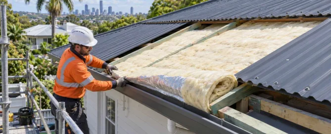 Illustration of a roofer fitting insulation beneath a partially installed metal roof on a Brisbane home.